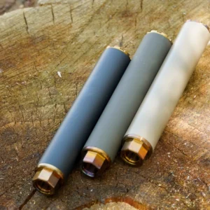 Three gray cylindrical metal tubes with brass threaded ends resting on a rough wooden surface.